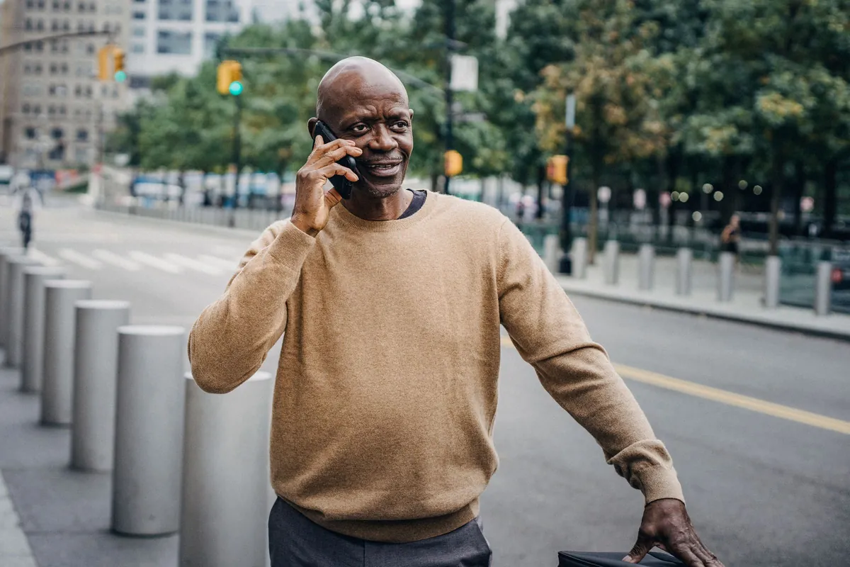 A man smiling as he talks on his phone.